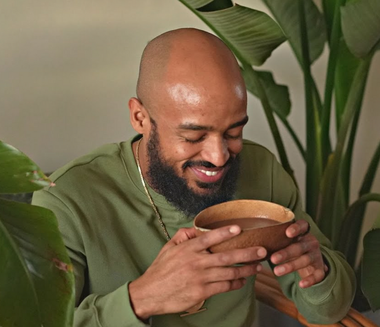 Man holding a wooden bowl in a casual setting with plants around